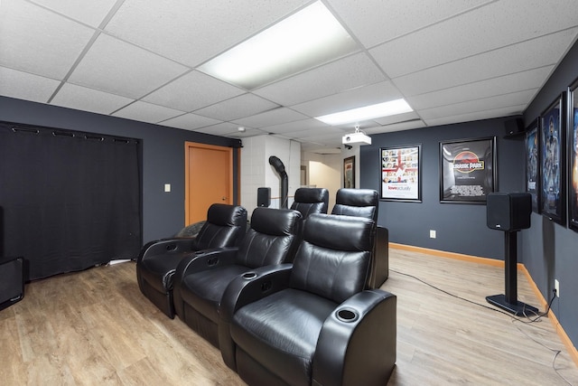 home theater with baseboards, a paneled ceiling, and light wood-style flooring