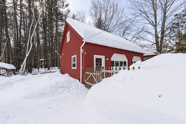 snow covered structure with an outbuilding