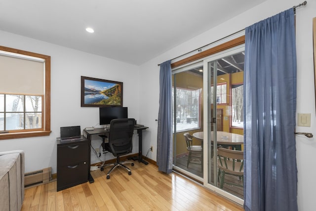 office area with a wealth of natural light, baseboard heating, light wood-style flooring, and baseboards