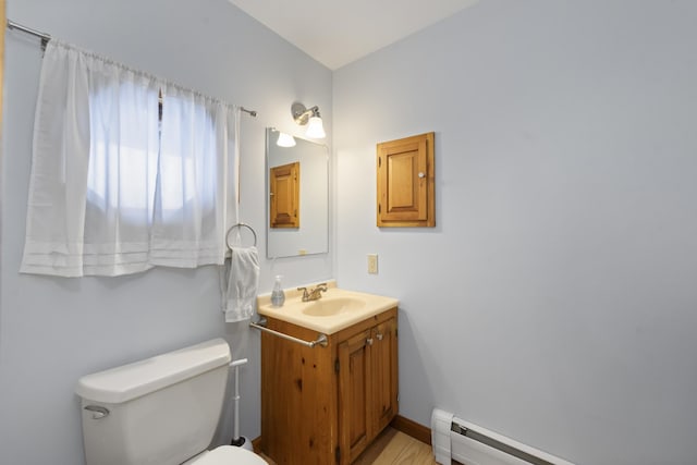 bathroom featuring a baseboard heating unit, toilet, vanity, and baseboards