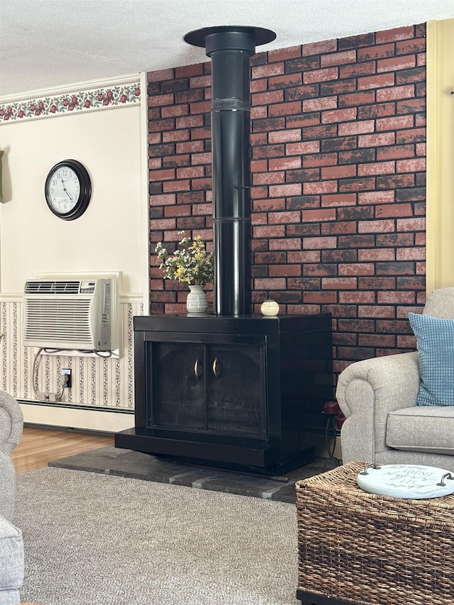 interior details with wood finished floors, a wood stove, a wall mounted air conditioner, a textured ceiling, and baseboard heating