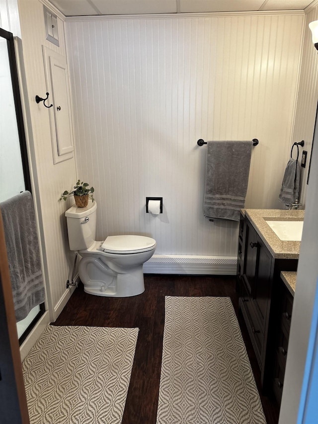 bathroom featuring baseboards, toilet, baseboard heating, wood finished floors, and vanity