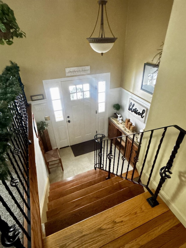 foyer entrance with wainscoting, wood finished floors, and stairs