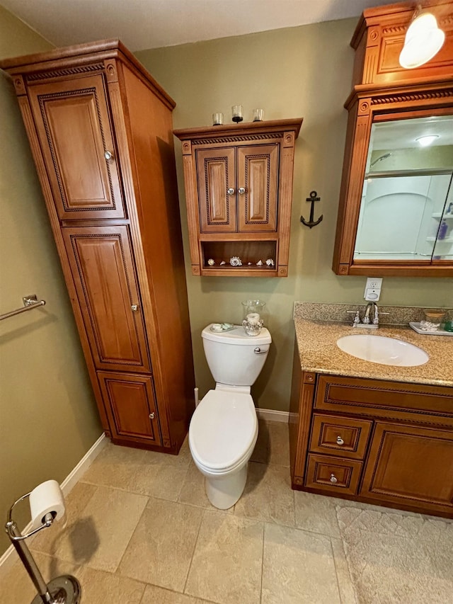 bathroom with toilet, vanity, and baseboards