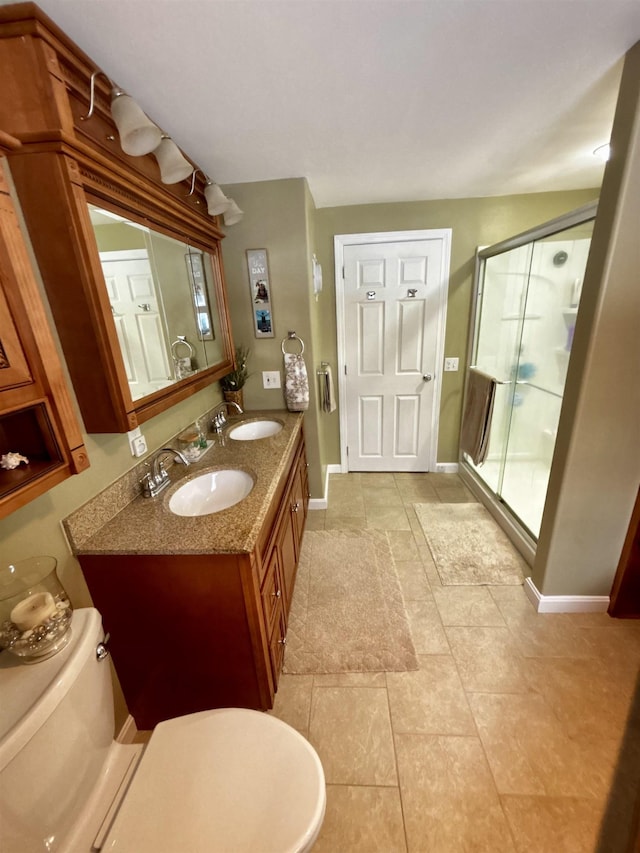 full bathroom featuring a shower stall, toilet, baseboards, and a sink