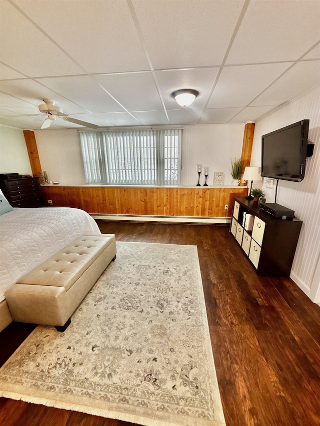 bedroom with wood finished floors, a drop ceiling, and ceiling fan