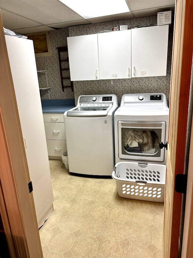 laundry room with wallpapered walls, washing machine and dryer, and cabinet space