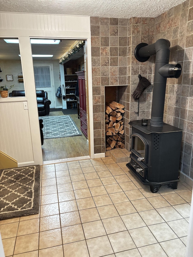 living room with light tile patterned floors, a textured ceiling, and a wood stove