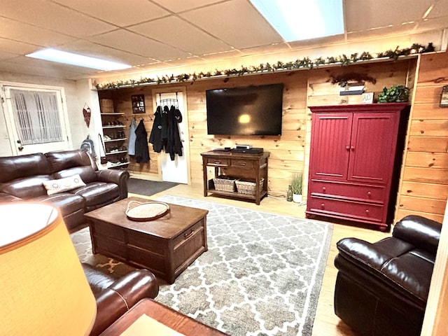 living area with a drop ceiling, wood walls, and wood finished floors