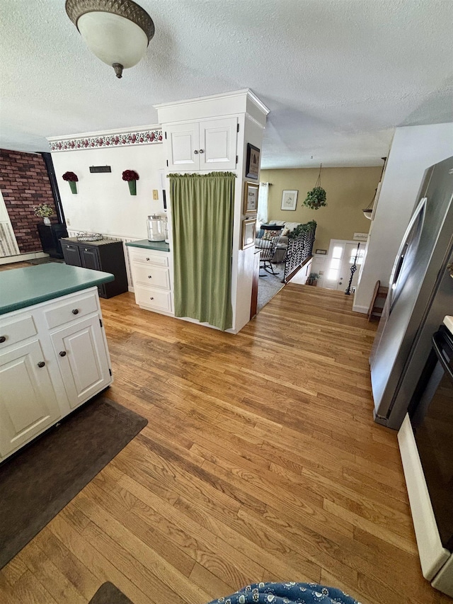 kitchen featuring a textured ceiling, white cabinetry, and light wood-style floors