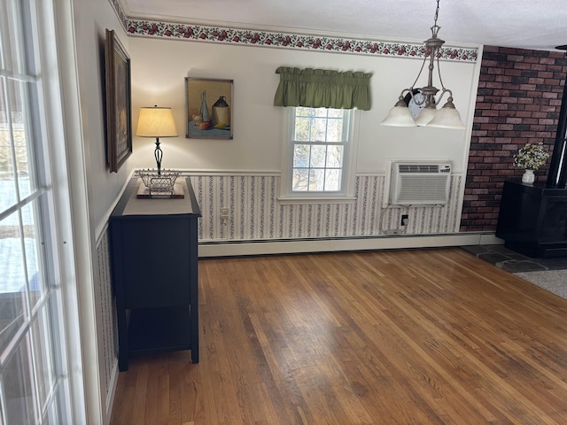 foyer featuring wood-type flooring, baseboard heating, a wood stove, and a wall mounted AC