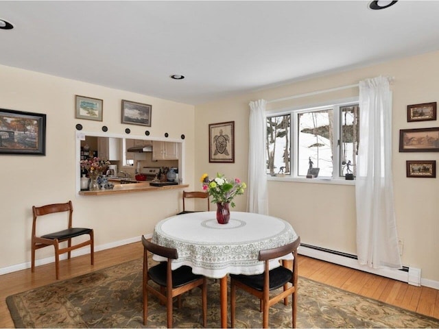 dining area featuring a baseboard heating unit, baseboards, and wood finished floors