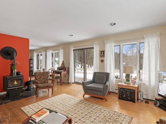 living room with light wood finished floors, recessed lighting, and a wood stove