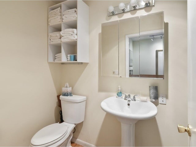 bathroom with a sink, baseboards, and toilet