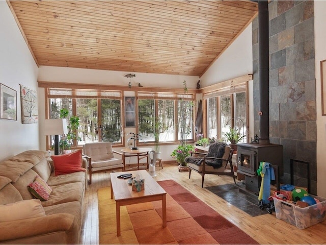 living area with high vaulted ceiling, wooden ceiling, a wood stove, and hardwood / wood-style flooring