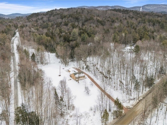 snowy aerial view with a mountain view and a wooded view