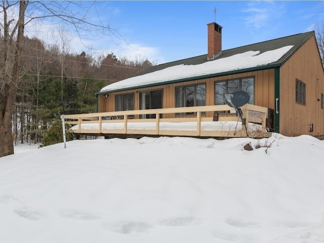 snow covered property with a deck and a chimney