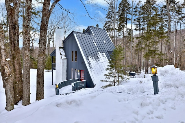 exterior space with a chimney, a garage, metal roof, and a standing seam roof