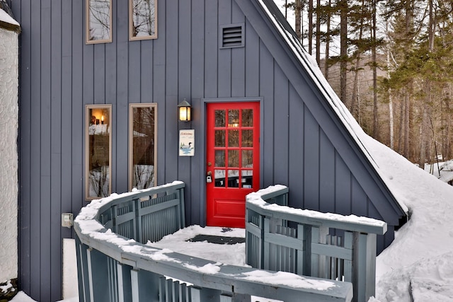 snow covered property entrance with board and batten siding