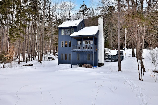 rear view of property with a balcony and a chimney