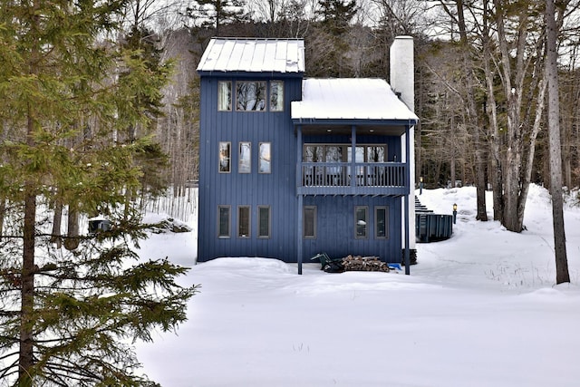 view of front facade with metal roof, board and batten siding, a chimney, and stairway