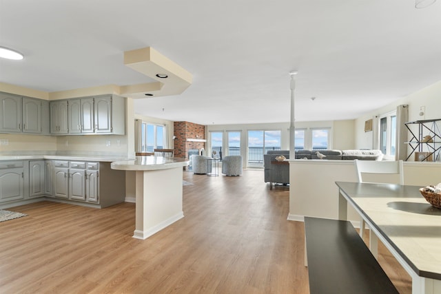 kitchen featuring light countertops, gray cabinets, open floor plan, and light wood-type flooring