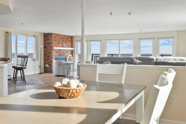 dining area featuring a fireplace, baseboards, and light wood finished floors