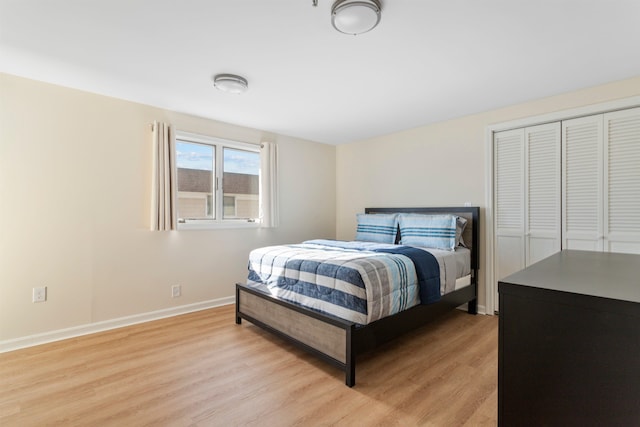 bedroom featuring light wood-style floors, baseboards, and a closet