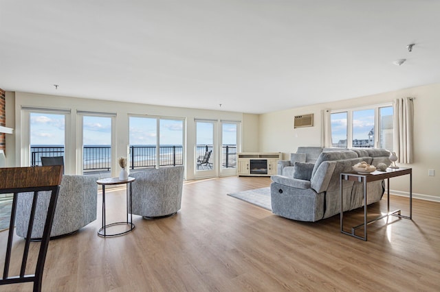 living area with wood finished floors, an AC wall unit, a fireplace, and baseboards