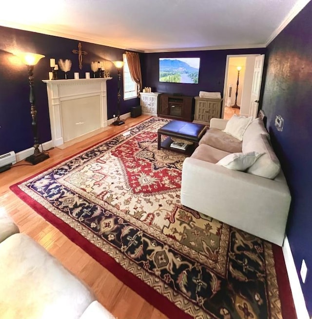 home theater room featuring baseboards, wood finished floors, a fireplace, and crown molding