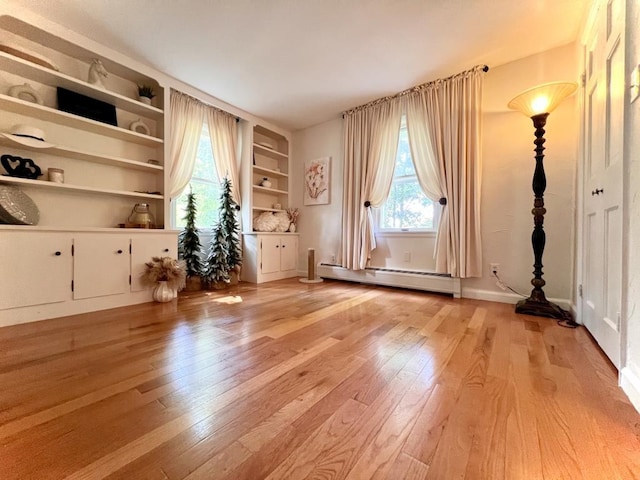 unfurnished room with baseboards, light wood finished floors, and a baseboard radiator