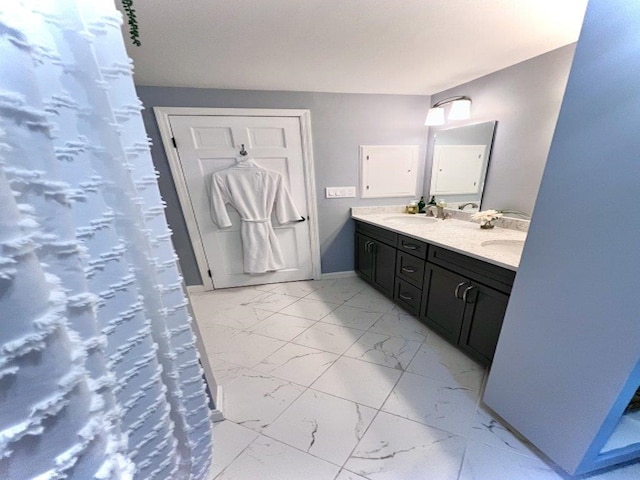 full bathroom with double vanity, baseboards, marble finish floor, and a sink