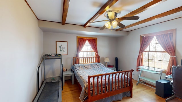 bedroom with beamed ceiling and wood finished floors