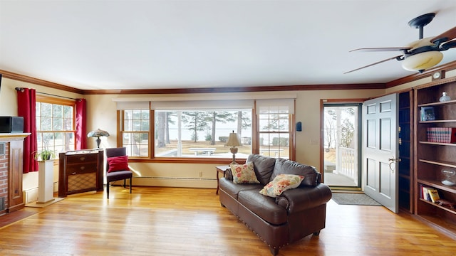 living room featuring light wood-style flooring, a brick fireplace, crown molding, and a baseboard radiator