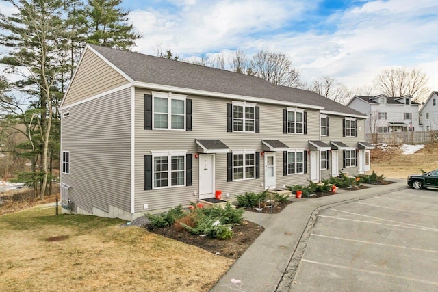 view of front of property with uncovered parking, a shingled roof, a front lawn, and entry steps