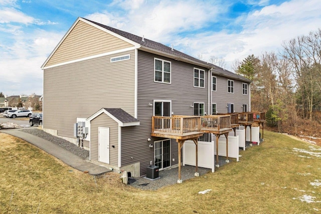 rear view of property featuring a yard, central AC unit, and a wooden deck