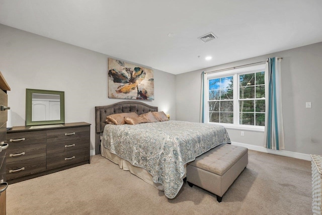 bedroom with visible vents, light carpet, and baseboards