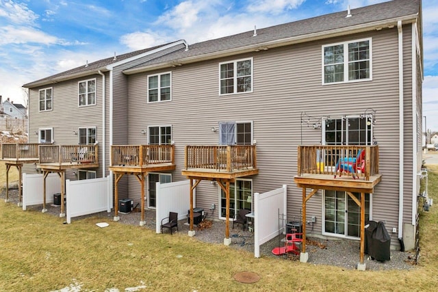 rear view of house featuring a deck, a yard, fence, and central AC