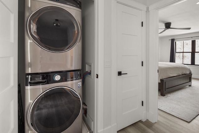 clothes washing area featuring ceiling fan, laundry area, wood finished floors, and stacked washing maching and dryer