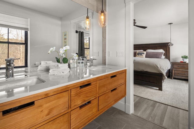 ensuite bathroom with a sink, connected bathroom, ceiling fan, and double vanity