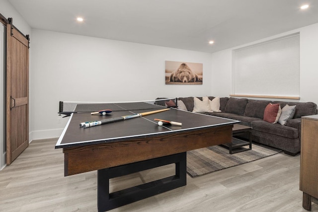 recreation room featuring a barn door, light wood-style flooring, and recessed lighting