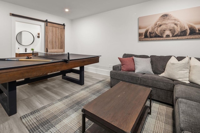 rec room with recessed lighting, a barn door, baseboards, and light wood finished floors