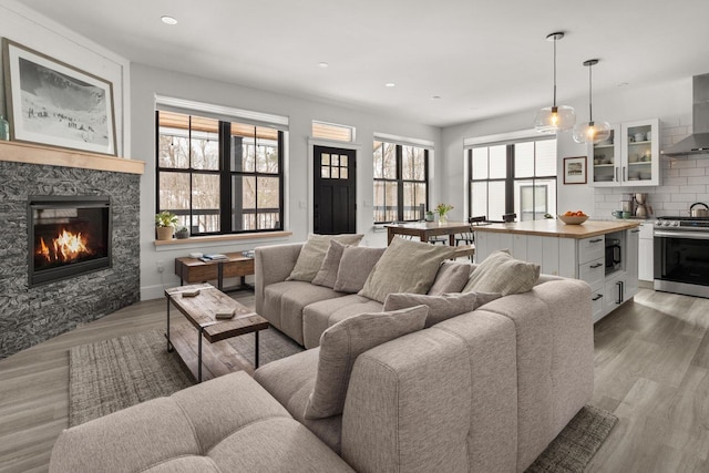 living room with a stone fireplace, recessed lighting, and light wood-style floors