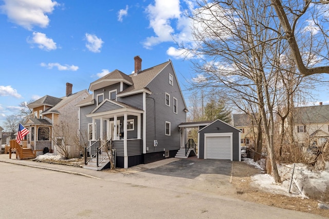 view of front of home featuring an outbuilding, driveway, a shingled roof, a garage, and a chimney