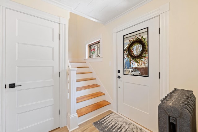 foyer with crown molding, baseboards, stairs, and light wood-style floors