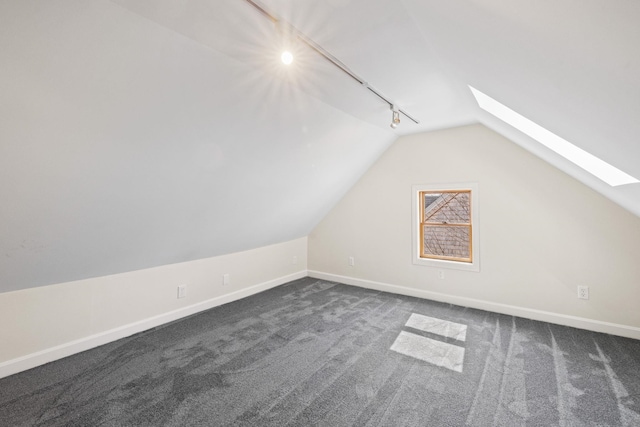 bonus room featuring lofted ceiling with skylight, baseboards, and dark colored carpet