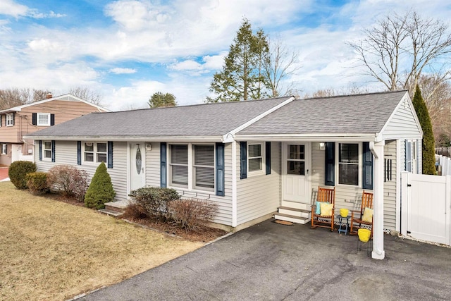 ranch-style house with a shingled roof, fence, aphalt driveway, entry steps, and a front yard