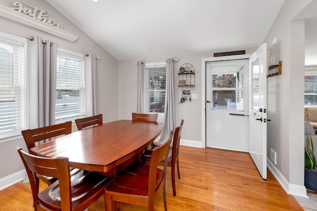 dining area featuring lofted ceiling, baseboards, and light wood-type flooring