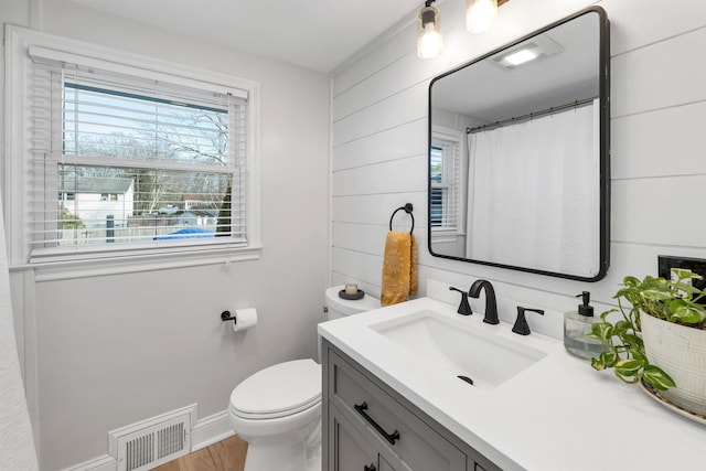 full bathroom with toilet, plenty of natural light, vanity, and visible vents