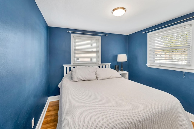 bedroom featuring baseboards, multiple windows, and wood finished floors